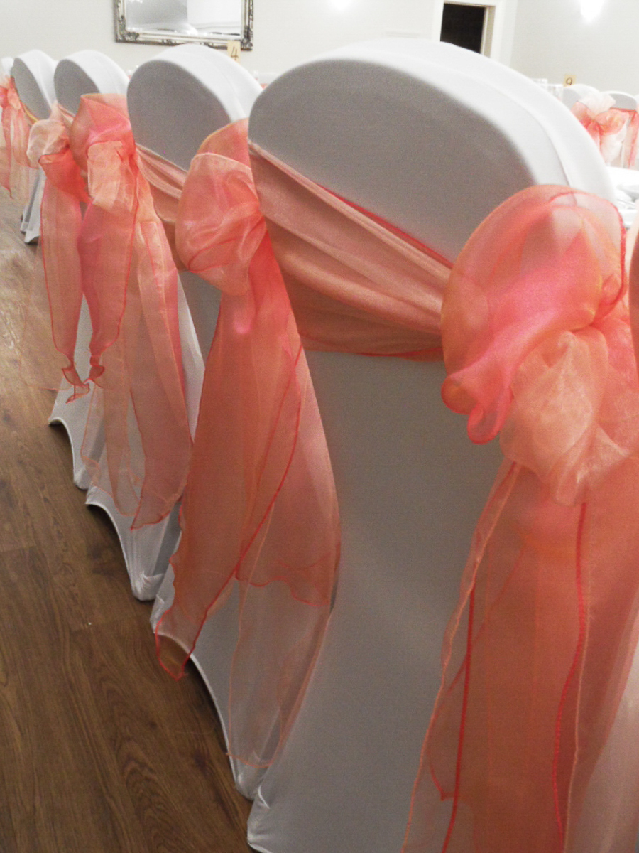 Coral stretch chair covers with rosette details at Barton Hall